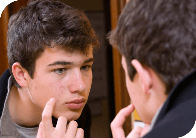 Un jeune homme regarde ses boutons dans le miroir