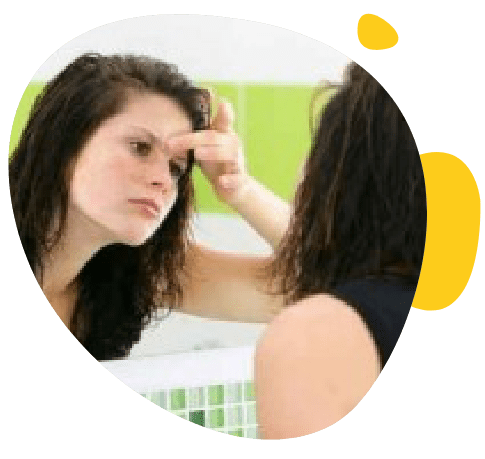 Une jeune fille se regarde dans un miroir de la salle de bain